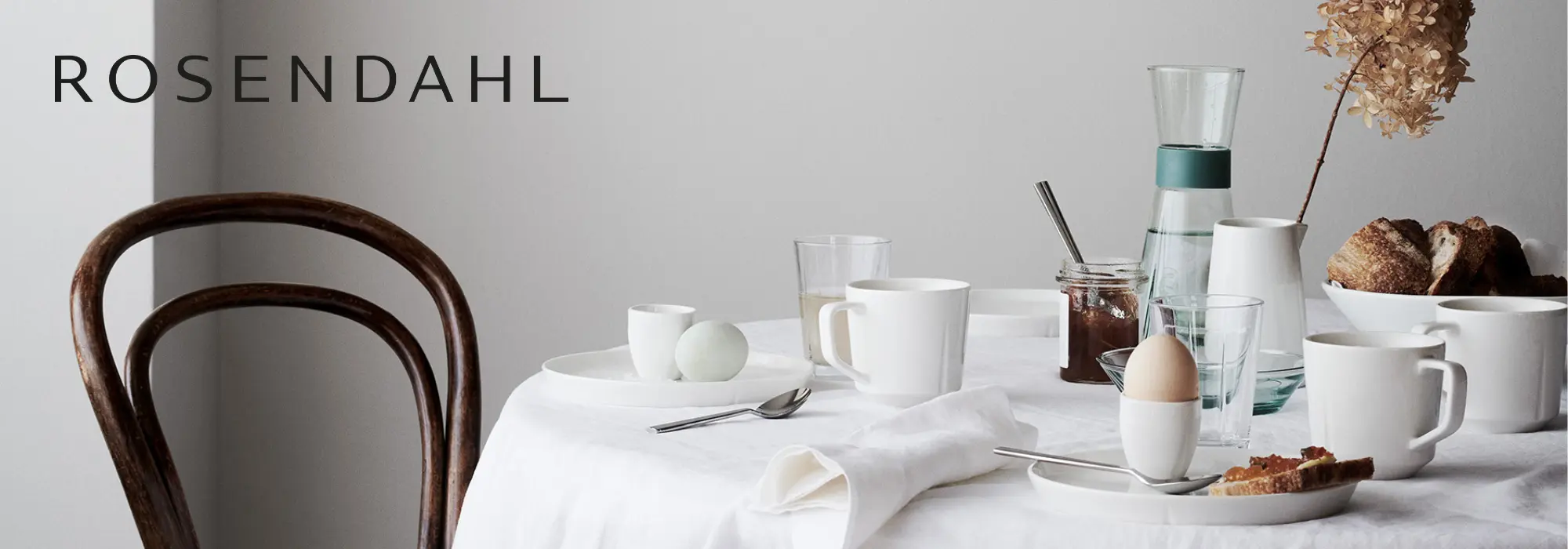Rosendahl Grand Cru servise med kopp, asjett, tallerken, glass og bestikk dekket på et hvitt frokostbord.